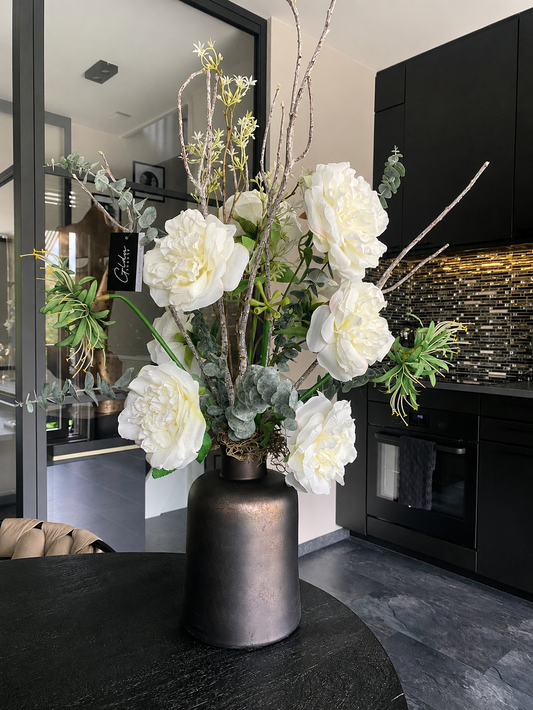 Wit kunstbloemstuk met pioenrozen en eucalyptus in luxe design vaas.