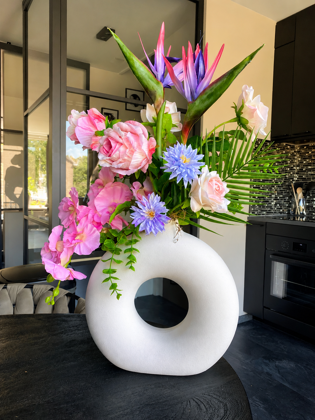 Bouquet de fleurs artificielles rose et violet avec des oiseaux de paradis dans un vase blanc