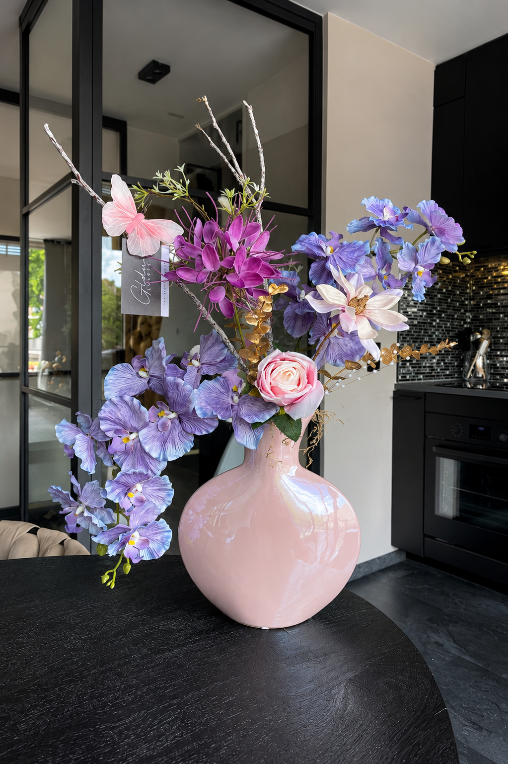 Luxe zijdebloemstuk met paarse orchideeën, roze roos en pastelbloemen in lichtroze designvaas