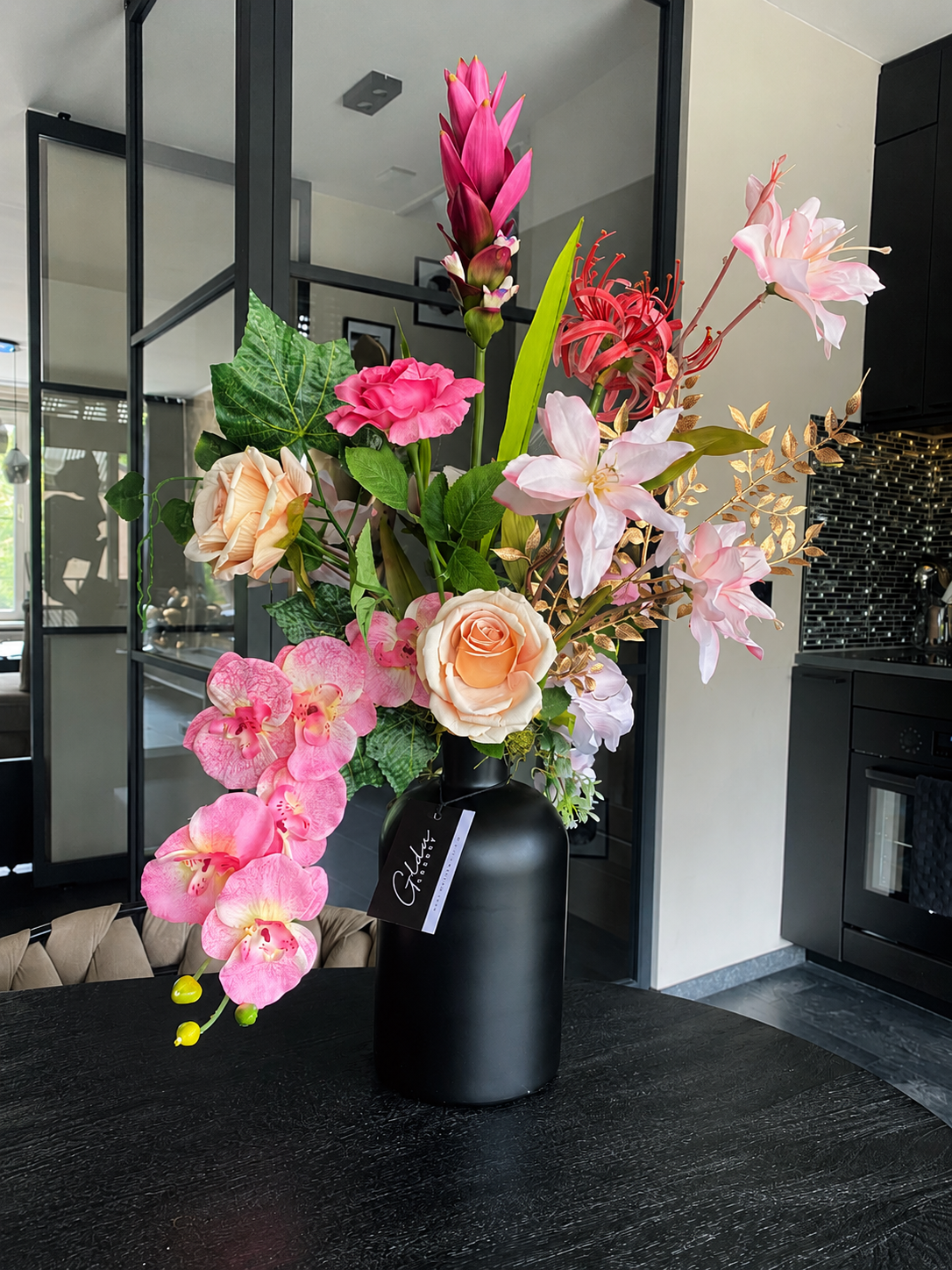 Luxe kunstbloemstuk met roze orchideeën, rozen en zwarte vaas voor een stijlvol en modern interieur
